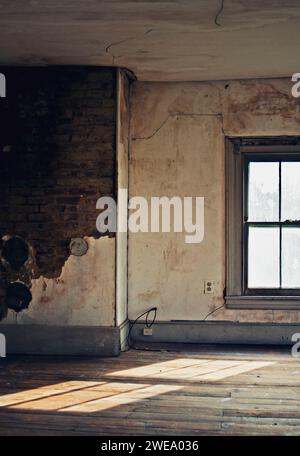 Sunlight streaming through a tall window in an empty historic farmhouse. Stock Photo