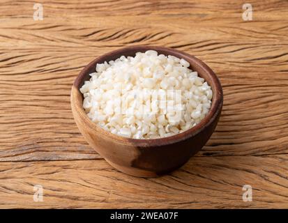 Dried canjica, hominy or white corn on a bowl over wooden table. Stock Photo