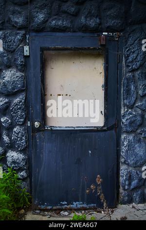 Weathered Blue Door in Black Stone Wall, Abandoned Hotel, Ohio Stock Photo