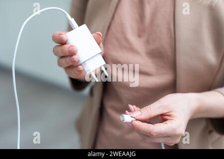 Close up of hand holding USB charging cable for phone with white background.  Stock Photo