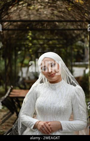 Smiling beautiful bride standing under the parking arch looks camera with smile and posing Stock Photo