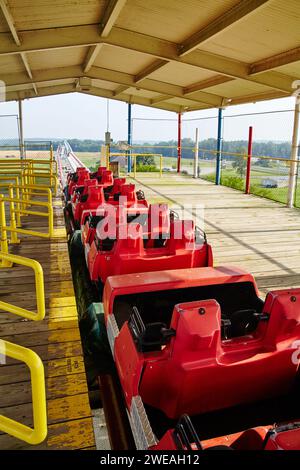 Empty Red Roller Coaster Cars at Rural Amusement Park, Eye-Level View Stock Photo
