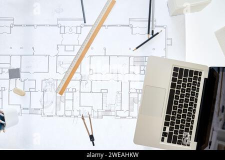 Top view background image of architects workplace with blueprints on table and laptop, copy space Stock Photo