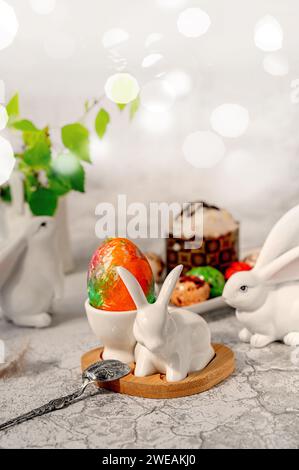 Happy Easter, Easter painted egg in the shape of a bunny shaped egg cup on the table. Stylish holiday table decor. Naturally dyed Easter eggs and spri Stock Photo