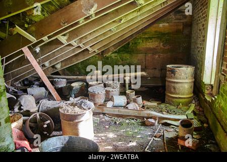 Rusty Barrels in Abandoned Industrial Building with Moss Overgrowth Stock Photo