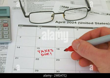 TAXES DUE! is shown written on a calendar by hand. The USA Internal Revenue Service IRS deadline for calendar year 2023 filing is April 15, 2024. Stock Photo