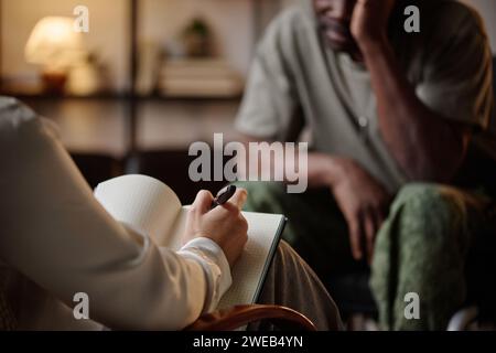 Psychologist taking notes while black war veteran having conversation with her at private session Stock Photo