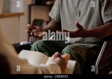 Black war veteran emotionally speaking during private therapy session, psychologist taking notes Stock Photo