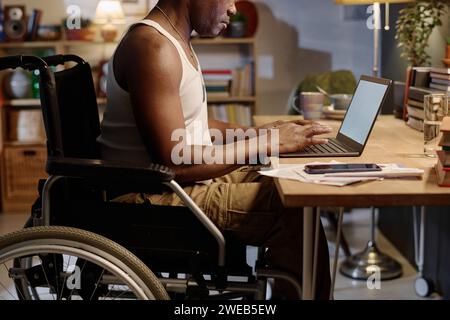 Unrecognizable african american senior man in wheelchair working from home on his portable computer Stock Photo