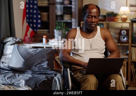 Retired african american man with physical disability working from home on his laptop Stock Photo