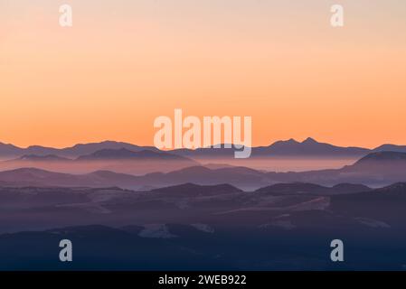 High mountain ranges in dense fog. Layers of mountains in the haze during sunset. Multi-layered foggy mountains. Stock Photo