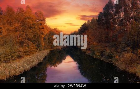 Beautiful dramatic landscape of lake in the autumn forest on the sunset sky background with reflection on water. Stock Photo