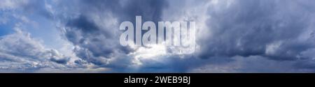 Dark clouds against a blue sky with sunbeams shining through. Sky panorama. Stock Photo