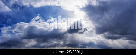 Cloudy sky in sunny weather with glowing rays through the clouds. Stock Photo