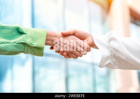 Two businesswomen in office suits shaking hands The concept of joyful business partners Stock Photo