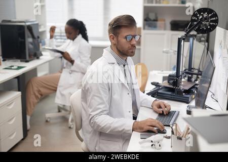 Male Technician Using Computer in 3D Printing Lab Stock Photo