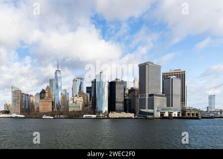 A skyline view of Lower Manhattan of New York from the bay with blue sky and clouds. Stock Photo