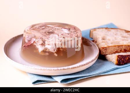 Jelly with meat, beef aspic, traditional dish. portion on plate with homemade bread. Stock Photo