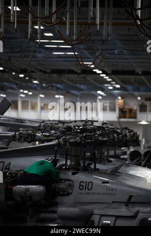 240122-N-FK754-1049 PACIFIC OCEAN (Jan. 22, 2024) Aviation Machinist’s Mate 3rd Class Bryan Solis, from Chicago, performs maintenance on an MH-60S Sea Hawk helicopter, assigned to Helicopter Sea Combat Squadron (HSC) 14, in the hangar bay of the Nimitz-class aircraft carrier USS Abraham Lincoln (CVN 72). The Abraham Lincoln Carrier Strike Group is underway in the U.S. 3rd Fleet area of operations conducting advanced tactical training that increases warfighting capability and tactical proficiency across all domains. (U.S. Navy photo by Mass Communication Specialist 3rd Class Eduardo A. Torres) Stock Photo