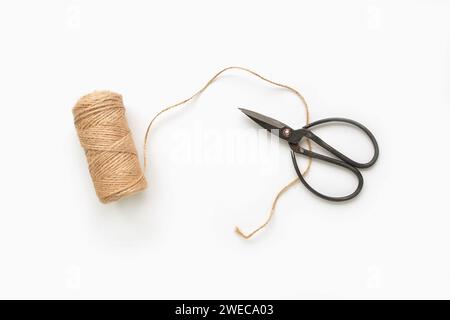 Rustic natural twine and old fashioned metal herb scissors isolated on white background in flat lay composition. Horizontal format with room for text. Stock Photo