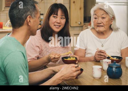 Elderly Japanese Mother with adult children having lunch at home. Concept of family, tradition and ethnic diversity. Stock Photo