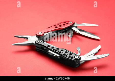 Compact portable multitool on red background, closeup Stock Photo