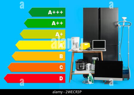 Energy efficiency rating label and different household appliances on light blue background Stock Photo