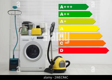 Energy efficiency rating label and different household appliances near window indoors Stock Photo