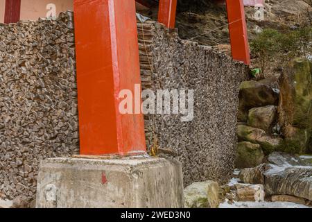 Cut firewood stacked neatly under arches of red wood on winter day in South Korea Stock Photo