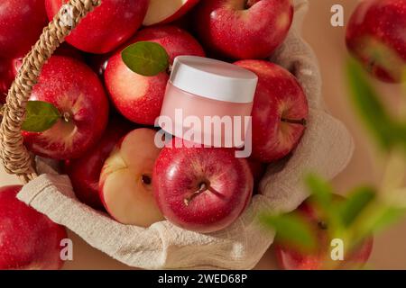 Bamboo basket with a stack of apples and a pink jar with empty label placed on top. Apple (Malus domestica) potentially reducing acne. Organic cosmeti Stock Photo