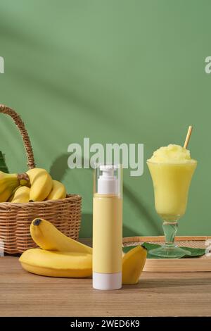 Pump bottle with empty label displayed with a glass of banana smoothie and a basket of bananas. Mockup of skin care branding with Banana (Musaceae) ex Stock Photo