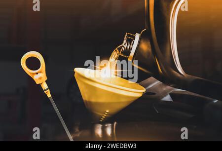 Engine oil poured into a funnel in the engine oil filler and oil dipstick on a dark background , Double exposure , Car maintenance service concept Stock Photo