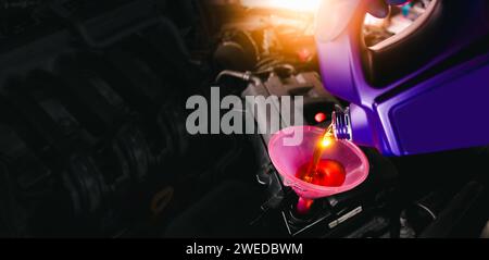 Engine oil poured into a funnel in the engine oil filler on a black background with copy space , Car maintenance service concept Stock Photo