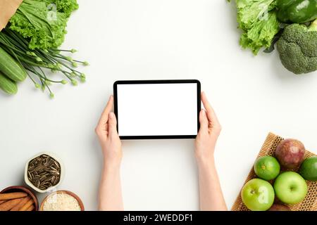 Hands of woman holding tablet computer with empty screen on table with groceries Stock Photo