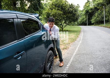 Asian businessman car broken has problems with car down during go to work in morning he pushing out Stock Photo