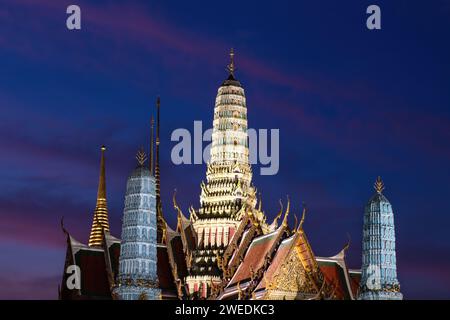 Grand Palace (Wat Phra Kaew) at night in Bangkok, Thailand. Buildings illuminated different colors. Indigo and violet colored sky in the background. Stock Photo