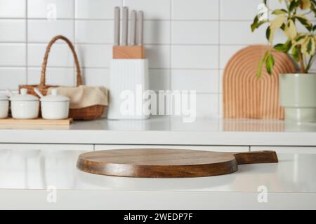 Kitchen interior shot with wooden cutting board, knife tray, spice boxes, bamboo basket and a small potted on white tile wall background. Blank space Stock Photo