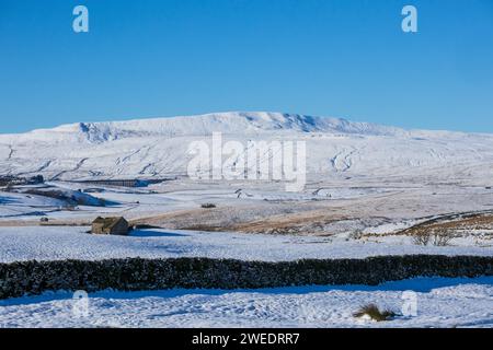 A distant view of the Ribblehead Viaduct under Whernside on a beautiful winter day in the Yorkshire Dales in England, with lots of snow on the ground. Stock Photo
