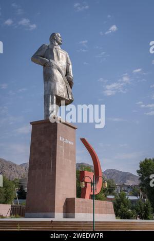 Vertical cityscape view of landmark Lenin statue standing on pedestal in public park with red sickle and hammer symbol, Khujand, Sughd, Tajikistan Stock Photo