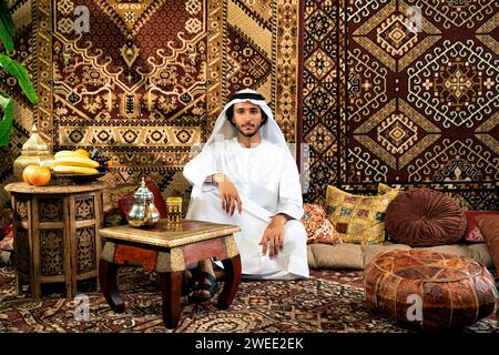 Man from emirati wearing kandura outfit spending time in an arabian traditional house in Dubai Stock Photo