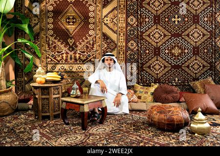 Man from emirati wearing kandura outfit spending time in an arabian traditional house in Dubai Stock Photo