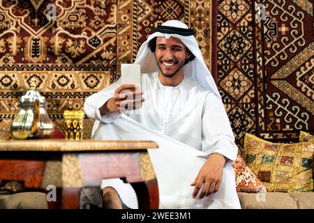 Man from emirati wearing kandura outfit spending time in an arabian traditional house in Dubai Stock Photo