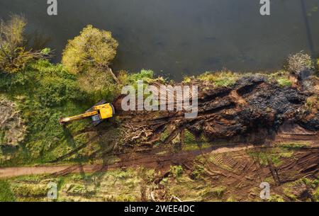 Aerial view of a yellow bulldozer digging a river to deepen and clean up a river channel to improve water flow. Stock Photo