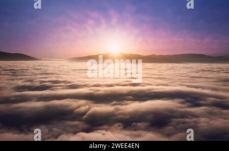 Mountains landscape with low dense fog in valley with beautiful cloudy sky from aerial view at sunset. Colorful nature background. Stock Photo