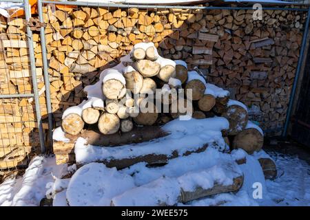 stack of firewood with snow in the winter time Stock Photo