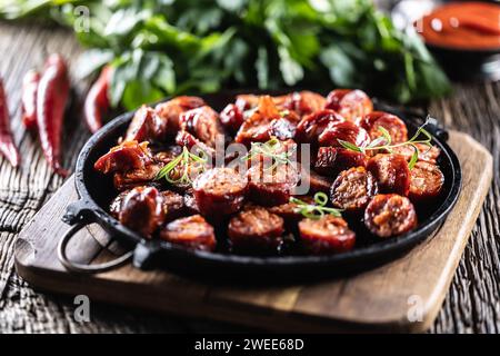 Sliced sausages fried with spices, bbq sauce and herbs - close up. Stock Photo