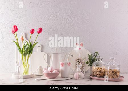 Chic kitchen background in delicate pastel colors, decorated for the Easter holiday with rabbits, flowers, eggs. White cookware Stock Photo