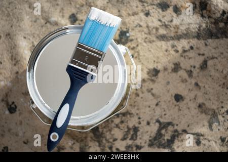 A new nylon handled throw away decorators paint brush with resting on the top of a tin of emulsion paint used for property improvement Stock Photo