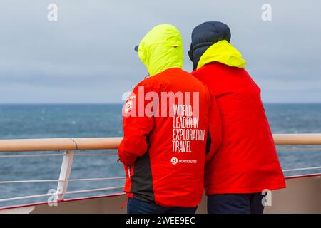 World Leader in Exploration Travel on back of Hurtigruten red jacket clothing on cruise ship at Greenland in July Stock Photo