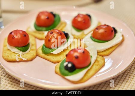Lady bug cracker with cream cheese and tomato on festive table Stock Photo